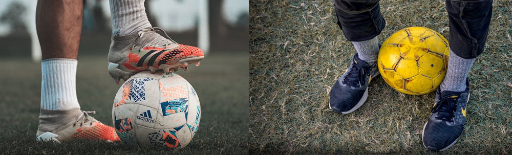 person standing on an branded football with white socks and white football shoes standing on a football. A person in a branded running shoe in grey socks and black trousers holding a yellow football inbetween their legs.